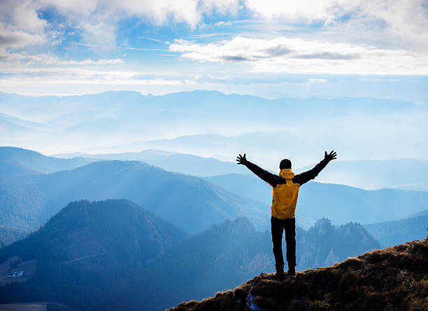istock Man stands on mountain with arms raised above head 172450544
