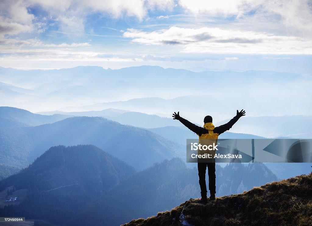 Homem de pé na montanha acima da cabeça com os braços para cima - Foto de stock de Amarelo royalty-free