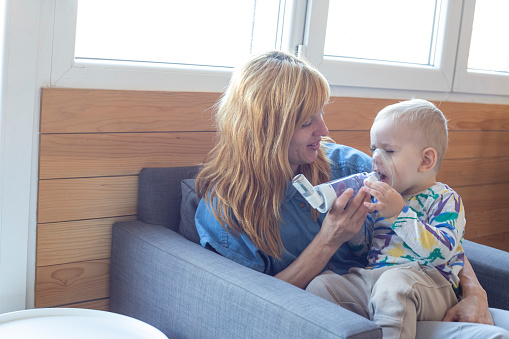 One year old boy inhaling asthma medicine with the help of his mother.