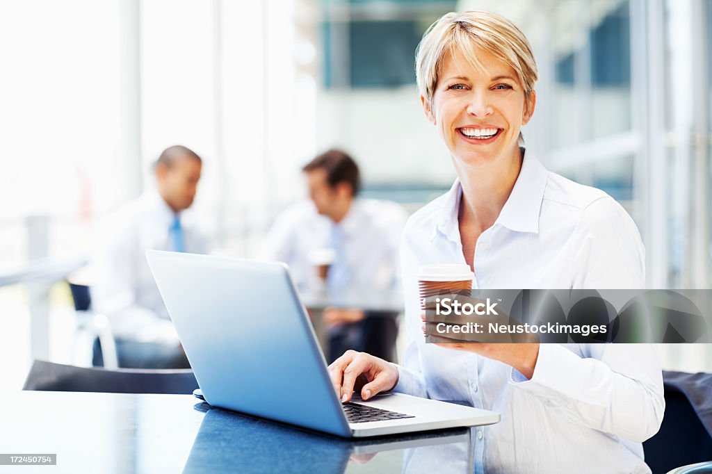 Weibliche Executive mit Laptop Holding Wegwerfbecher - Lizenzfrei Blick in die Kamera Stock-Foto