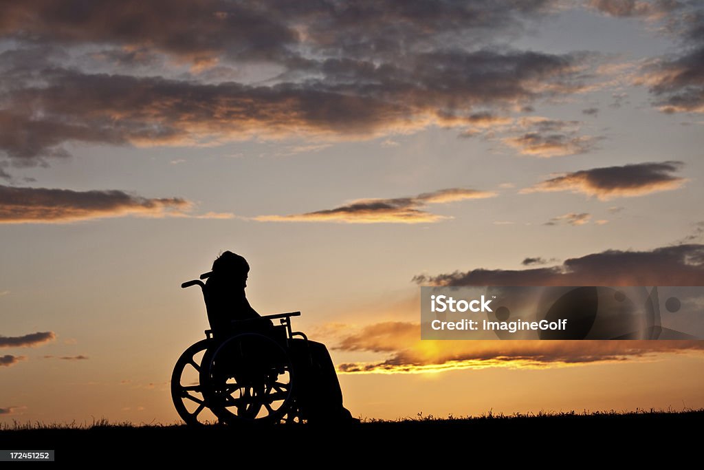 Silhouette of Sad Injured Boy in a Wheelchair A silhouette of a sad injured boy in a wheelchair. Adolescence Stock Photo