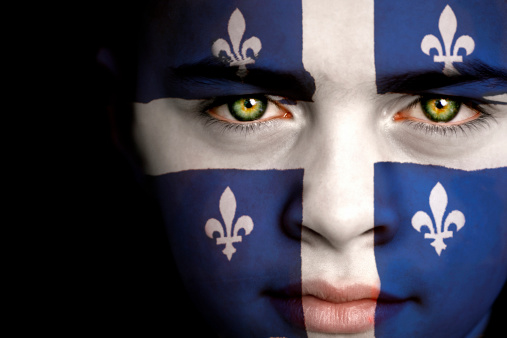 Portrait of a boy with the flag of Quebec painted on his face.