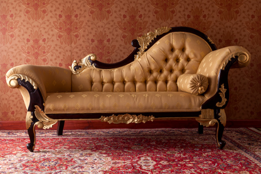 Antique black and gold chaise lounge in red room