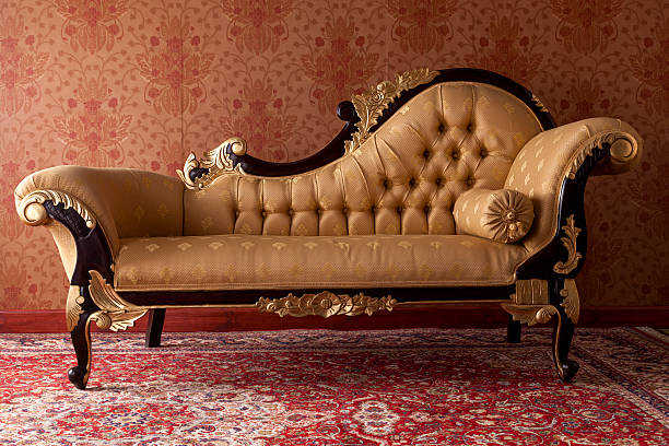 Antique black and gold chaise lounge in red room An ornate chaise longue in an upper class drawing room. chaise longue photos stock pictures, royalty-free photos & images