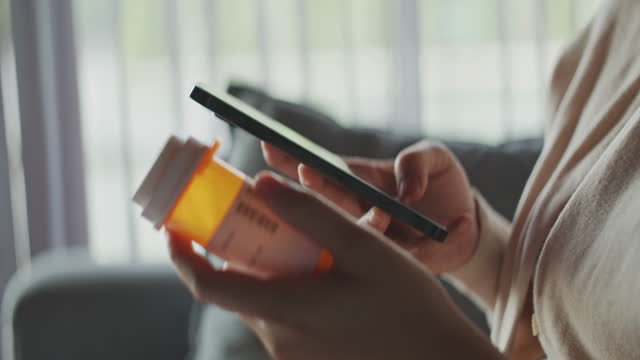 Hands with a smartphone and a pill bottle in close-up