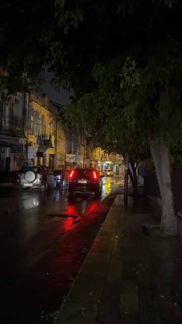 Traffic on a narrow street at night during a thunderstorm