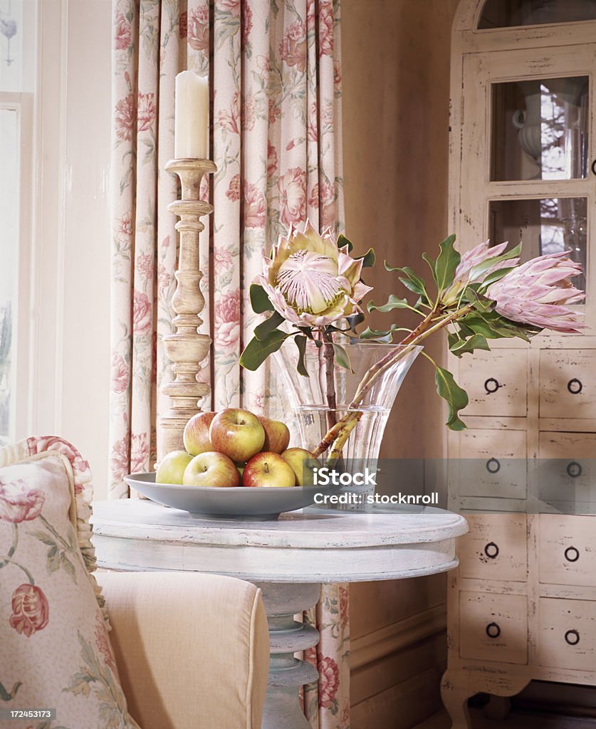 Interior of livingroom with flowers in the foregound A table with vase of flowers and curtains in front of wallpaper Knick Knack Stock Photo