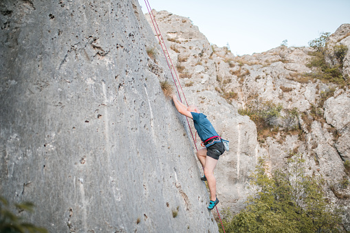 A male climber climbs a mountain using a special rope and climbing equipment