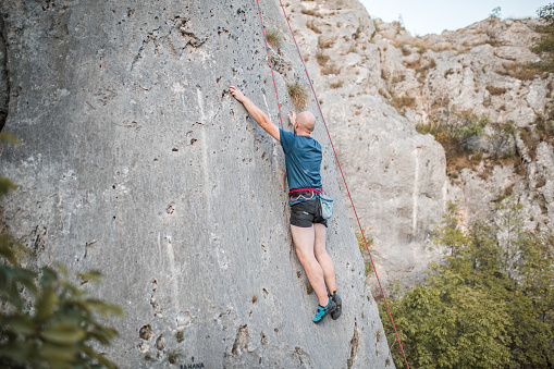 A male climber climbs a mountain using a special rope and climbing equipment