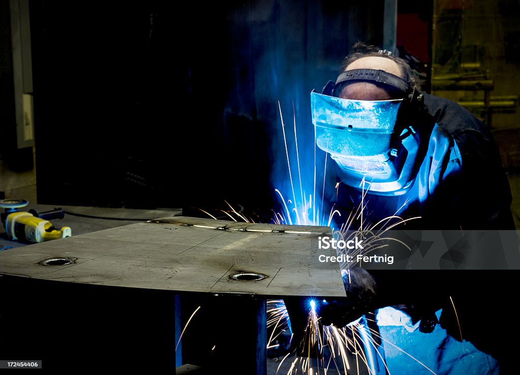 Welding in a metal manufacturing plant. A photograph of a welder working in a metal manufacturing plant. Sheet Metal Stock Photo