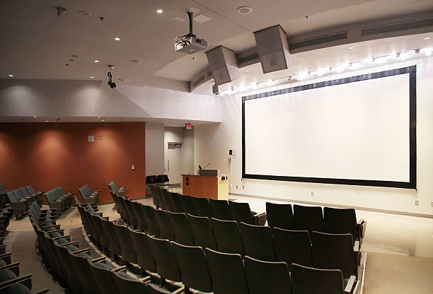 Modern University Lecture Hall "A modern university lecture hall, also used for conferences, presentations, and film screenings." projector screen classroom stock pictures, royalty-free photos & images