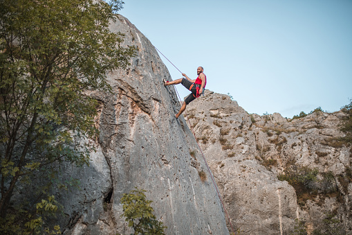 A female climber enjoys the adventure of climbing a mountain using rope
