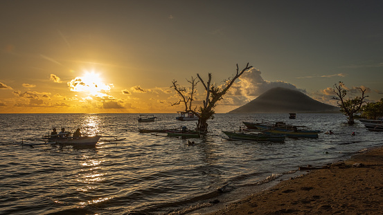 A beautiful sunset over Bunaken Island with the Manado Tua volcano in the background.