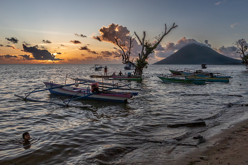 A beautiful sunset over Bunaken Island with the Manado Tua volcano in the background.