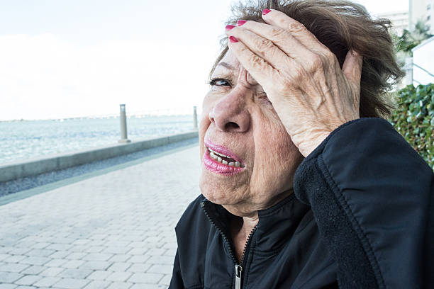 sensazione male - senior women defeat headache pain foto e immagini stock