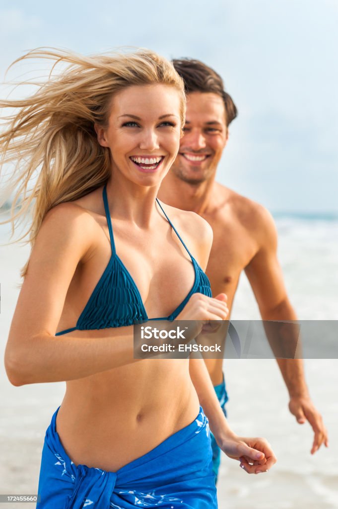 Jeune Couple Homme et Femme jouant dans les vagues sur la plage - Photo de Bikini libre de droits