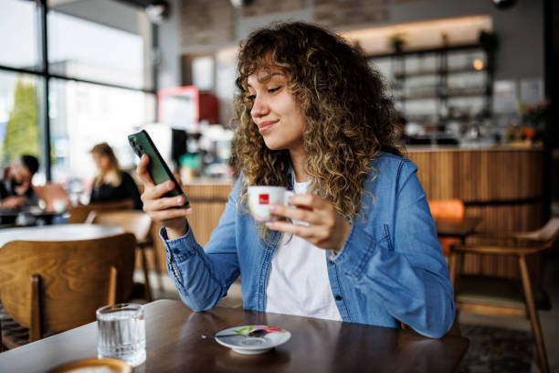istock Happy young woman using mobile phone and enjoying coffee at cafe 1724565252