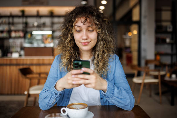 istock Happy young woman using mobile phone and enjoying coffee at cafe 1724565253