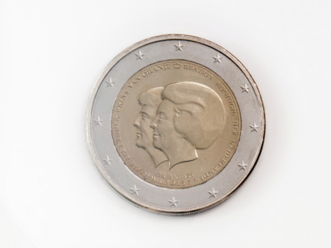 Close-up of a Dutch 2 Euro coin, isolated on white. The coin is used and shows scratches on the surface. It shows a profile of Queen Beatrix of the Netherlands (until 2013) and King Willem Alexander  of the Netherlands (from april 2013) a. The coin was issued in 2013
