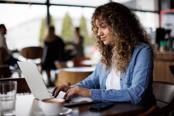 istock Young woman sitting in coffee shop and using laptop 1724570596