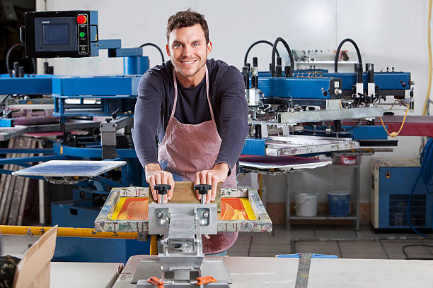 homem operação de equipamentos de impressão de tela - young men printing plant printing press factory - fotografias e filmes do acervo