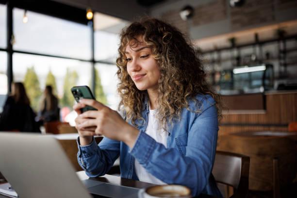 istock Young smiling woman texting on mobile phone at a cafe 1724572208