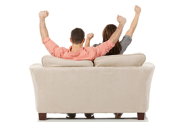 Couple sitting on couch raising hands Couple sitting on couch raising handshttp://www.twodozendesign.info/i/1.png couch back stock pictures, royalty-free photos & images