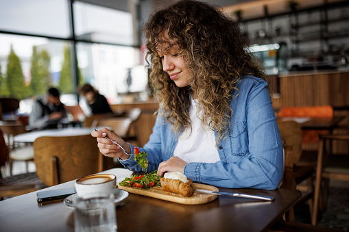 Young smiling woman enjoying healthy breakfast at a cafe