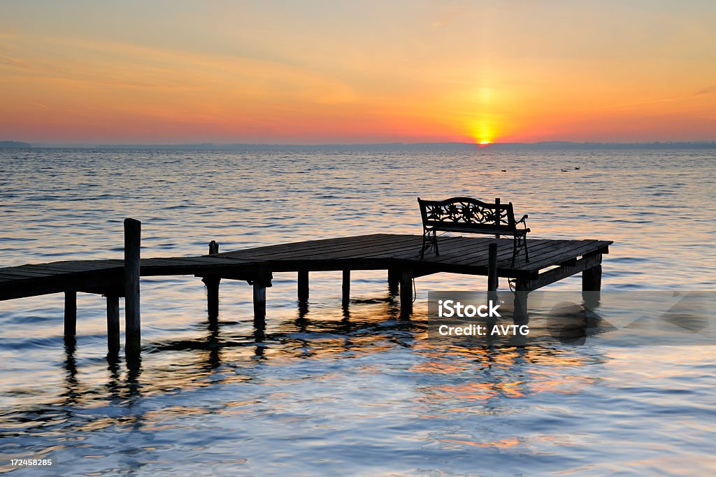 Bench on Dock by Lake at Sunrise Beach Stock Photo