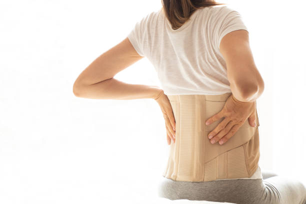 Woman with a corset on her back to support her back from pain in the back and spine, Medical concept, spinal support, wearing a brace at home stock photo