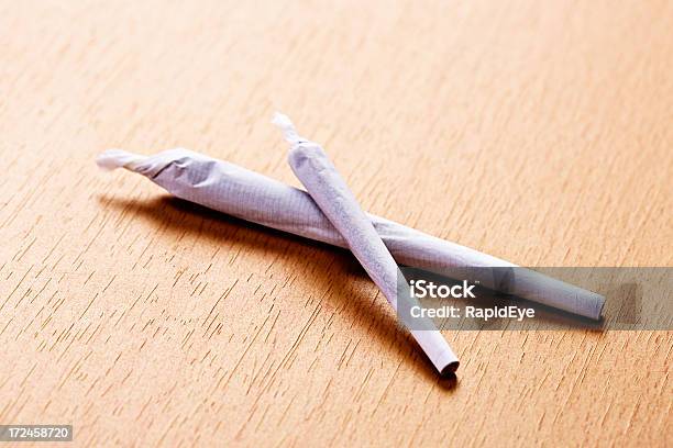 Two Marijuana Joints Big And Small On Wooden Surface Stock Photo - Download Image Now