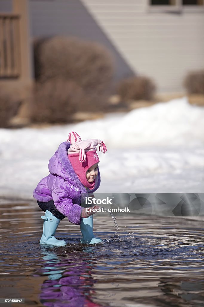 Niña jugando en la primavera en un charco - Foto de stock de 12-17 meses libre de derechos