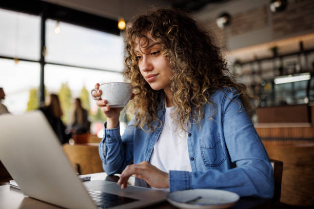 istock Young woman drinking coffee while working on laptop at a cafe 1724593033