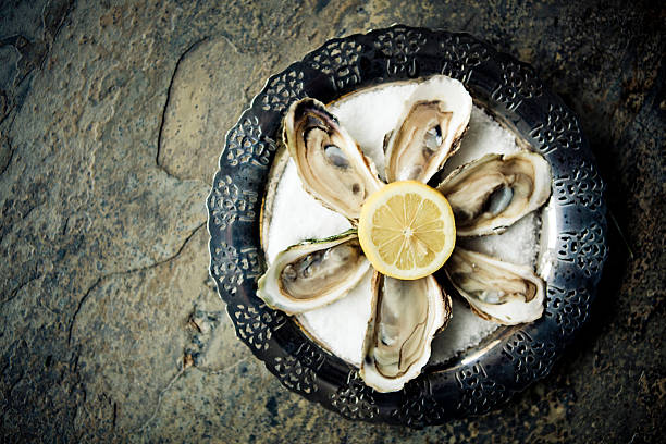 Oysters Ready-to-eat Caraquet Oysters with lemon on a vintage silver plate. silver platter stock pictures, royalty-free photos & images