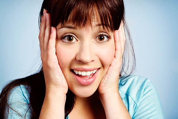 istock Pretty brunette smiles in delighted surprise, hands to her head 172460003