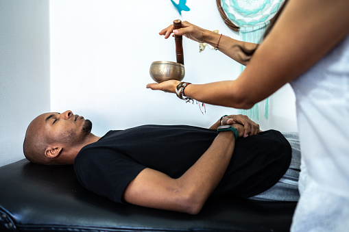 Therapist playing rin gong while performing music therapy at spa