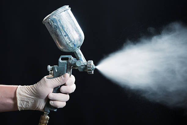 istock Disposable gloved hand spraying white paint from spray gun 172461291