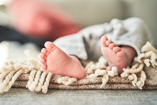 Close-up of little legs of a newborn baby on rug. Tiny foot of newborn baby.