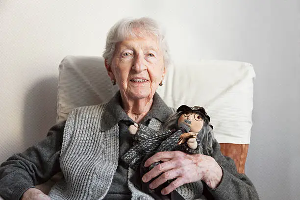 porttrait of a 90 years old woman, with her handmade doll