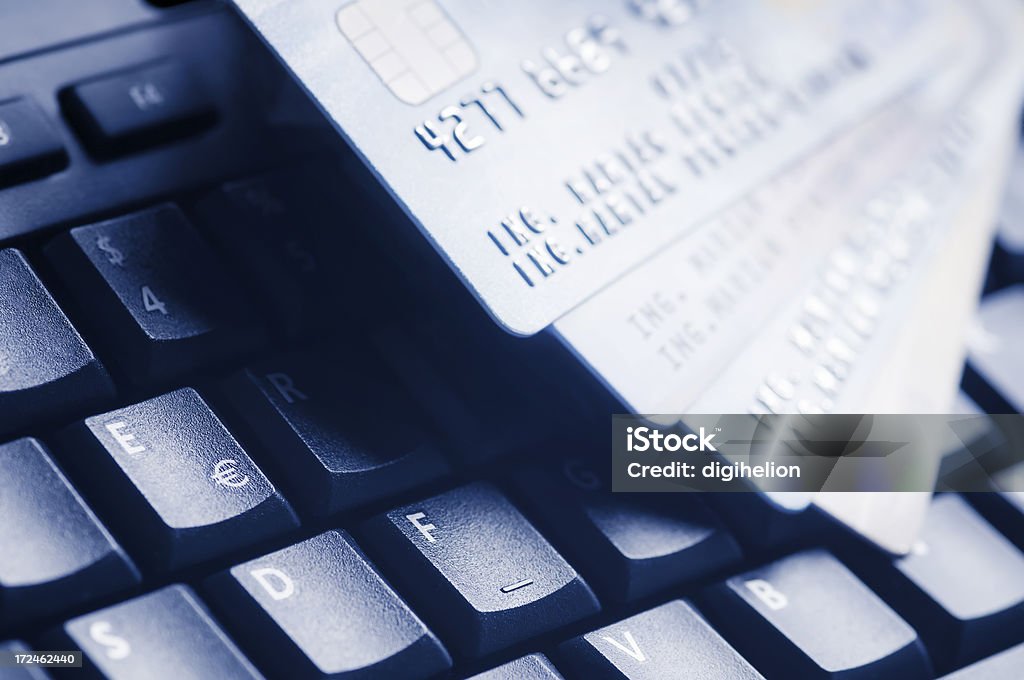 Credit cards on computer keyboard Macro of four credit cards on a computer keyboard. Dark blue hue. Accessibility Stock Photo