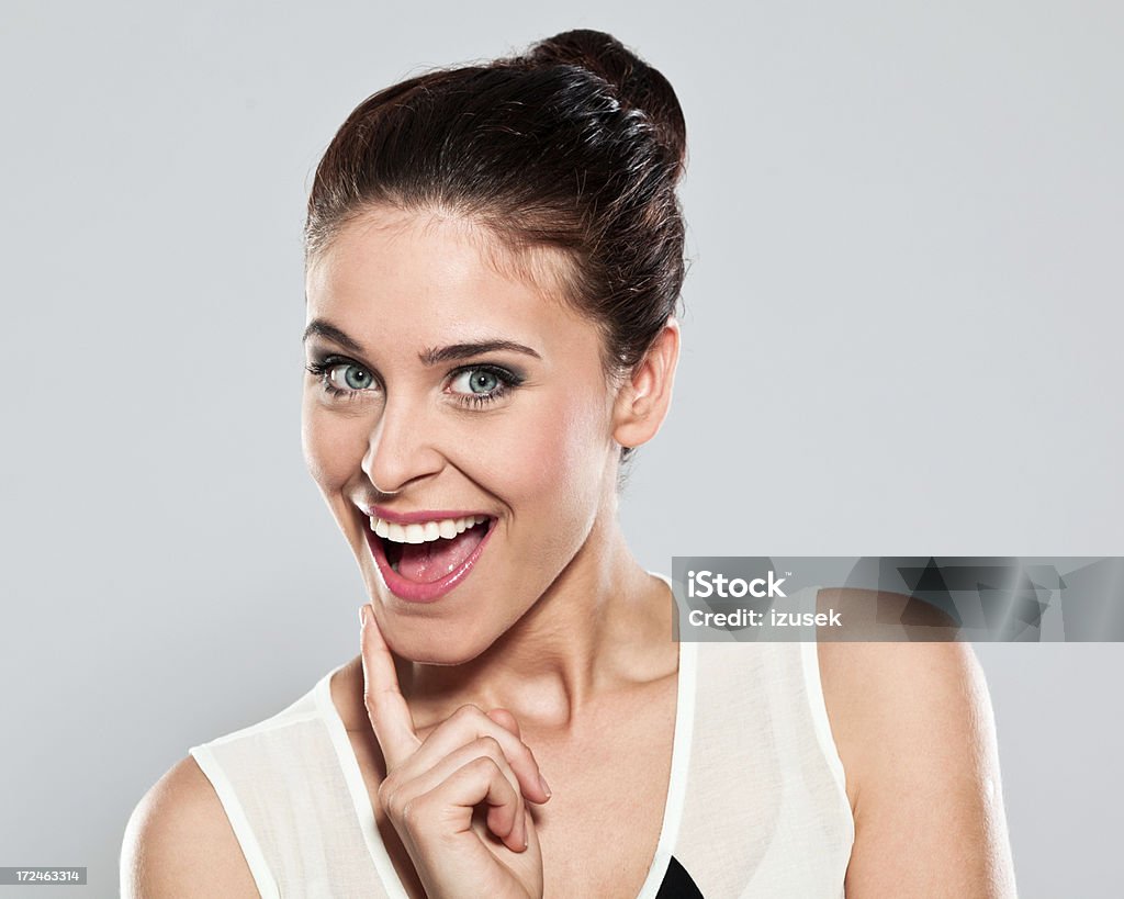 Happy young woman, Studio Portrait Portrait of excited young woman smiling at the camera. Studio shot on a grey background. 20-24 Years Stock Photo