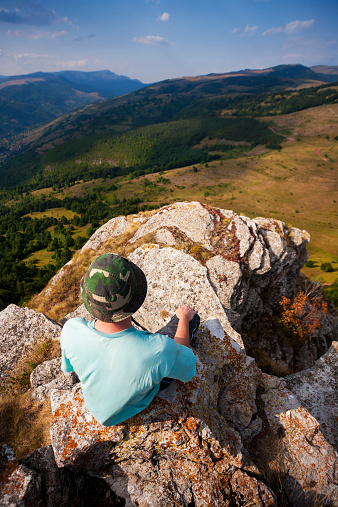 Hiker sitting alone on the mountain peak enjoying the view