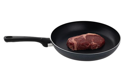 Raw steak in a pan on a white background. Raw piece of beef close-up in a frying pan isolated on white background.