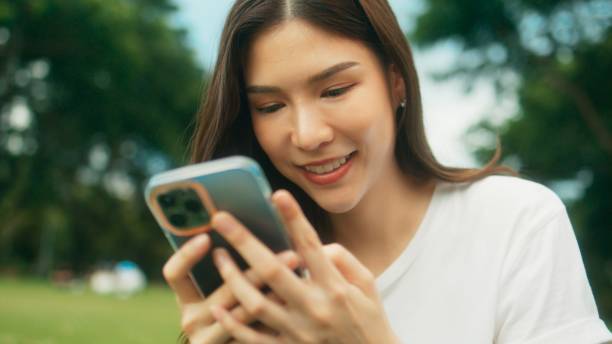 istock Beautiful Asian female university student doing activities, studying, reading, writing and sitting on green grass in city park 1724640496