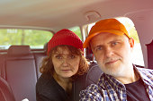 mature couple in a car wearing colorful caps/beanie