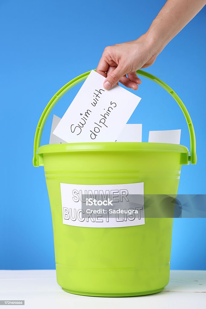 A bucket of different things to do in the summer Unrecognizable person adding a note to a summer bucket list Summer Stock Photo