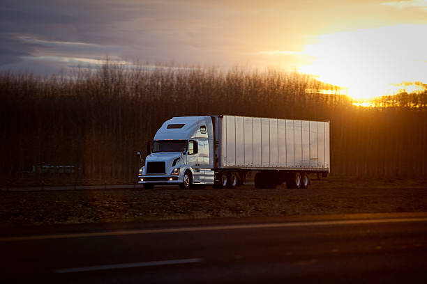 Semi tractor trailer on highway at sunset. stock photo