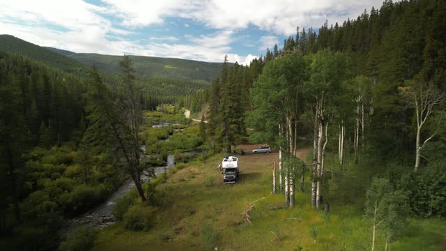 Aerial of RV camped along creek in beautiful Colorado forest in summer near Pitkin