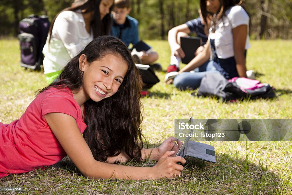 Tecnología: Latin teen girl tableta digital. Amigos de fondo. Park - Foto de stock de 12-13 años libre de derechos