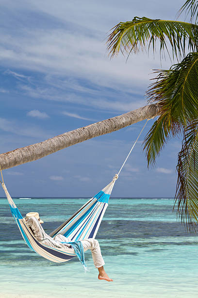 istock Young man relaxing in hammock hanged on a palm tree 172467356
